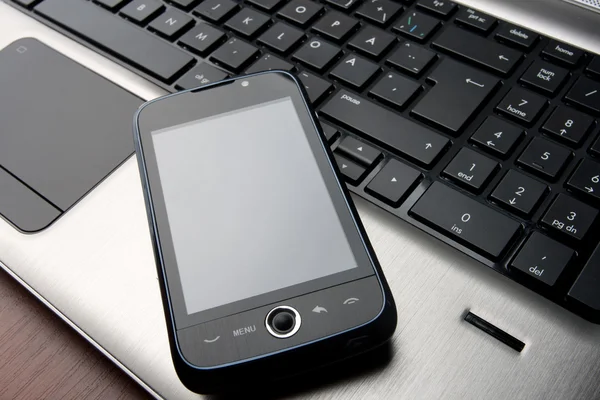 Téléphone moderne avec écran tactile sur clavier d'ordinateur portable — Photo