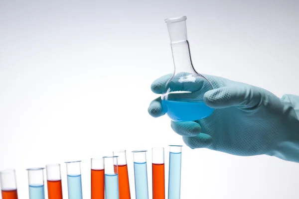 Cientista trabalhando em um laboratório, vidro contendo cor líquida — Fotografia de Stock