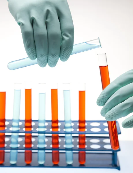Forskare som arbetar i ett laboratorium, glas som innehåller flytande färg — Stockfoto