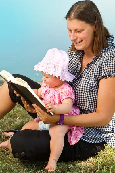 Niña leyendo libro con su madre — Foto de Stock