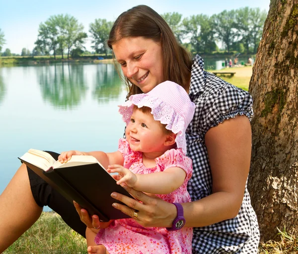Petite fille lisant le livre avec sa mère — Photo