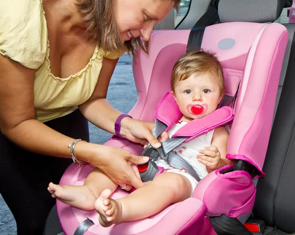 Woman fastening her son on a baby seat — Stock Photo, Image