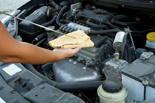 Auto mechanic checking oil — Stockfoto