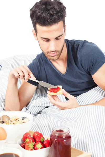 Homem está tomando café da manhã na cama — Fotografia de Stock