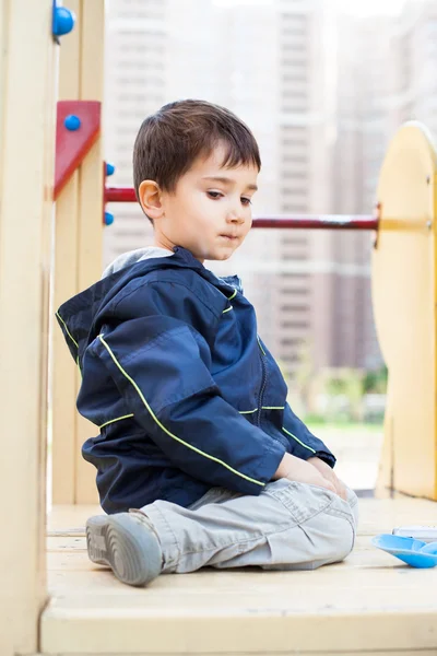 Chlapec sedí na hřišti — Stock fotografie