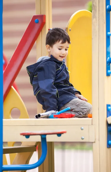 Мальчик сидит на детской площадке — стоковое фото