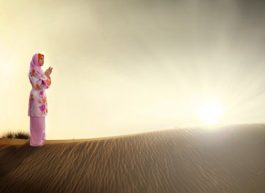 Muslim woman praying on the desert clipart