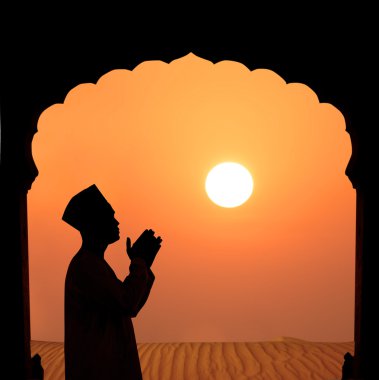 Silhouette of a muslim male praying on the desert clipart