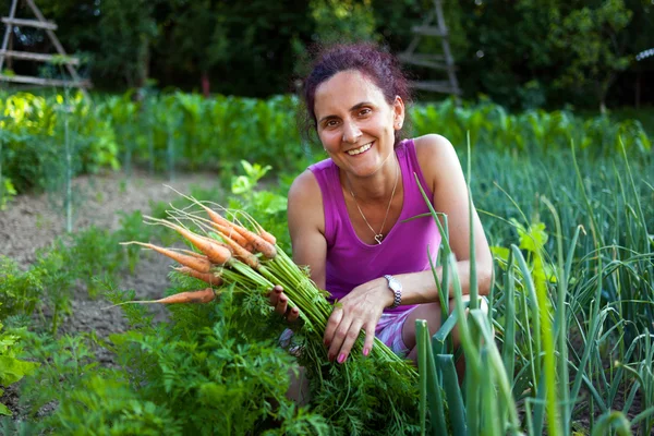 Mujer joven agricultora sosteniendo verduras — Foto de Stock