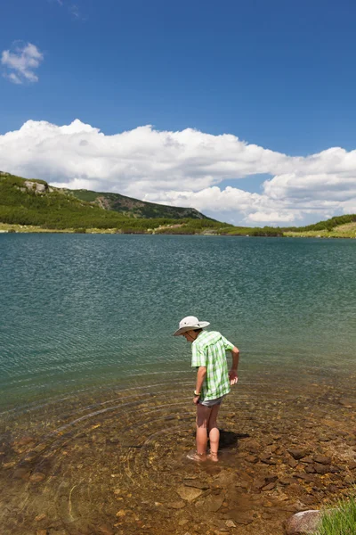 Ребенок в шляпе, босиком в озере — стоковое фото