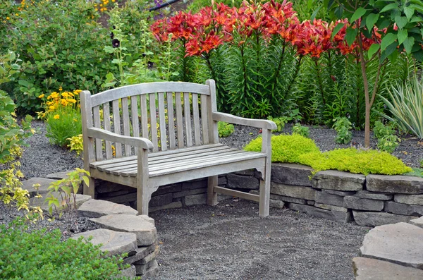 Деревянная скамейка в саду лилий — стоковое фото