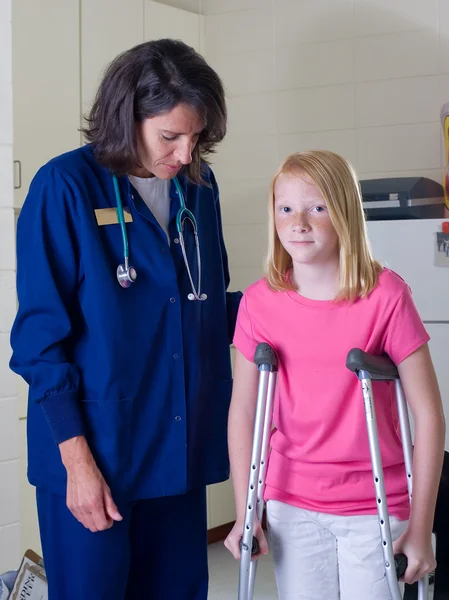 Молода дівчина на милицях з медсестрою Ліцензійні Стокові Зображення