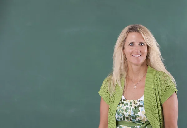 Teacher standing by chalkboard — Stock Photo, Image