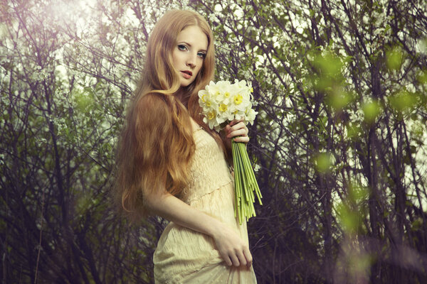 Portrait a beautiful young woman with flowers in the garden. Fashion photo