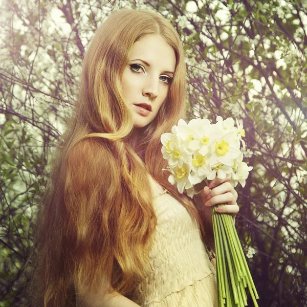 Retrato de una hermosa joven con flores en el jardín — Foto de Stock