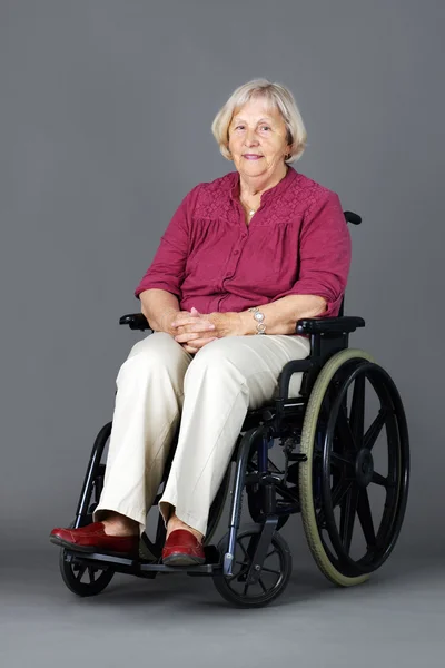 Senior mulher em cadeira de rodas sobre cinza — Fotografia de Stock