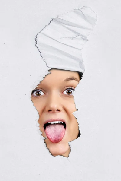 Pulling tongue behind ripped paper — Stock Photo, Image