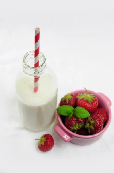 Láhev mléka a pohár s jahodami — Stock fotografie