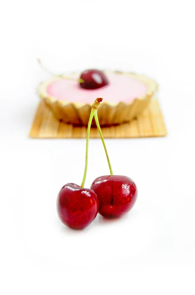 Cherries with cherry tart in the background — Stock Photo, Image