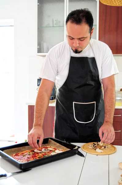 stock image Young man in kitchen making pizza