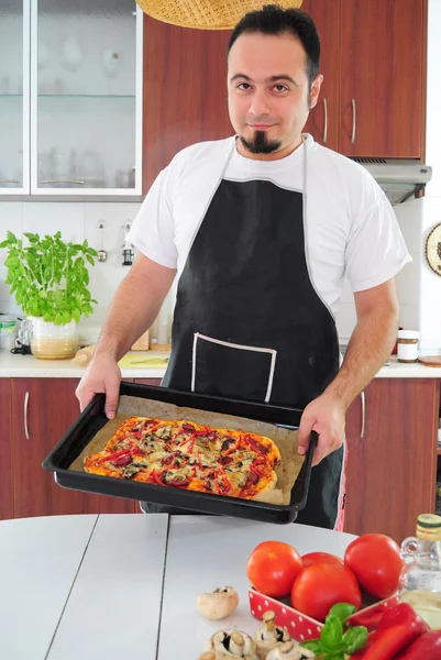 Junger Mann in Küche mit hausgemachter Pizza — Stockfoto