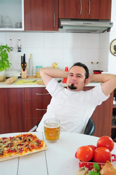 Mladý muž v kuchyni těší domácí pizza — Stock fotografie