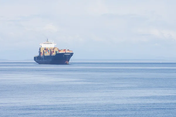 Vrachtschip op blauw water bij dageraad — Stockfoto