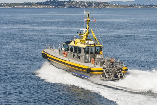 Barco piloto amarillo y plateado que corta a través del agua azul — Foto de Stock
