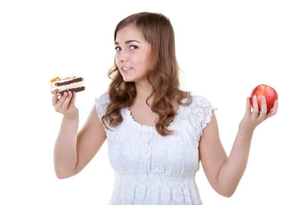 Fiatal gyönyörű nő választhat édes sütemény és a piros Alma — Stock Fotó