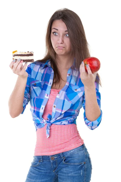 Girl in doubt with an apple and a cake — Stock Photo, Image