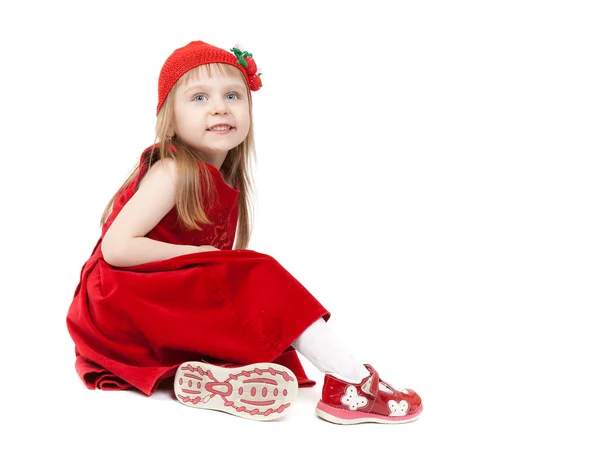 Wunderschönes vierjähriges Mädchen in rotem Kleid und Hut, das auf einem Stuhl sitzt. — Stockfoto