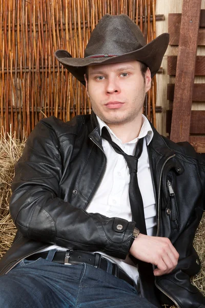 Saman üzerinde oturan geleneksel kıyafeti ile yakışıklı genç kovboy. — Stok fotoğraf