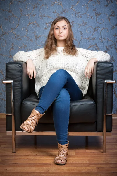 Retrato de una chica en una silla sobre un fondo de pared retro — Foto de Stock