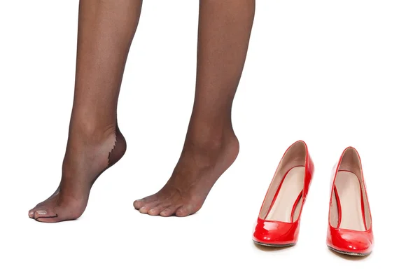 Устали женские ноги на белом фоне рядом с красными туфлями — стоковое фото