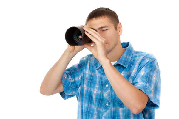 Handsome young man holding camera lens like it was spyglass on w — Stock Photo, Image