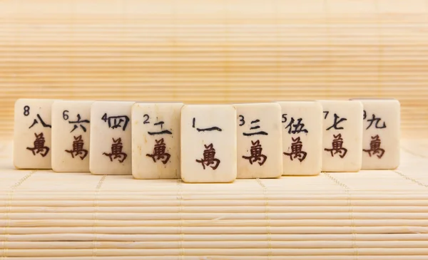 Velho jogo chinês mahjongg no fundo tapete de bambu — Fotografia de Stock