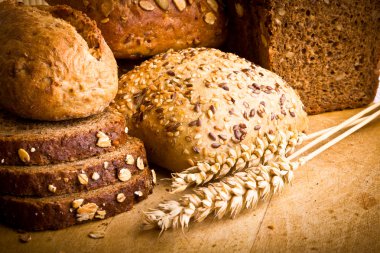 Collection of baked bread on wooden background clipart
