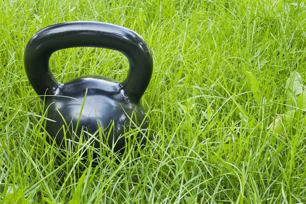 Kettlebell de ferro pesado na grama — Fotografia de Stock