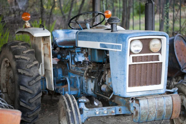 Gamla blå traktor i utomhus öppet skjul — Stockfoto