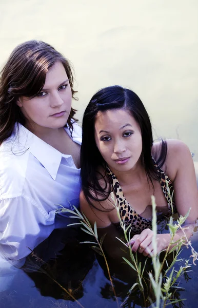 Dos mujeres jóvenes sentadas en el río al aire libre — Foto de Stock