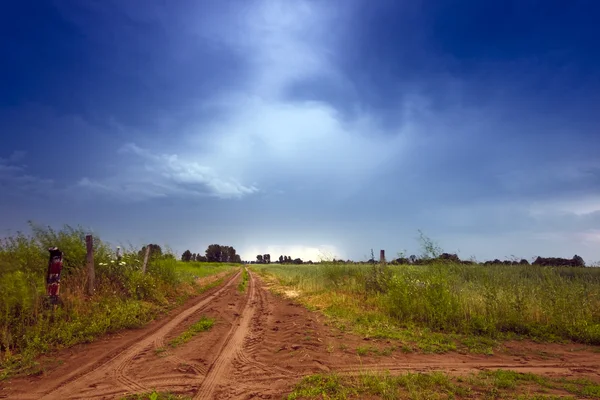 Route rurale et nuages orageux sombres — Photo