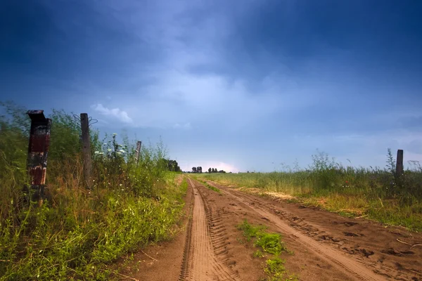 Сельская дорога и темные грозовые тучи — стоковое фото