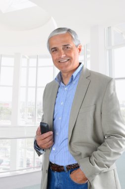 Businessman in Office Setting hodling Cell Phone clipart