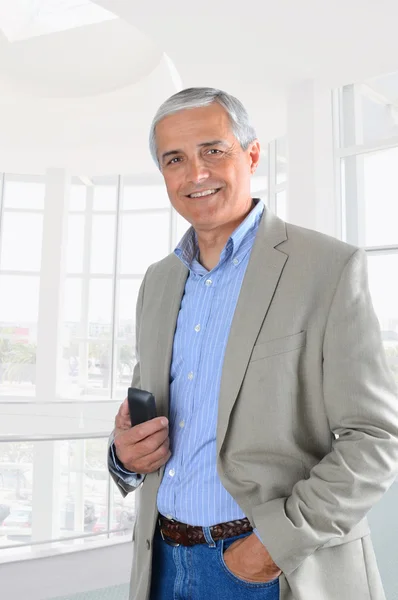 Empresário no escritório definindo hodling telefone celular — Fotografia de Stock
