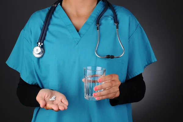 Медсестра с таблетками и стаканом воды — стоковое фото
