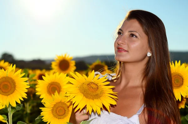 Mooi meisje in een veld bedrijf zonnebloem — Stockfoto