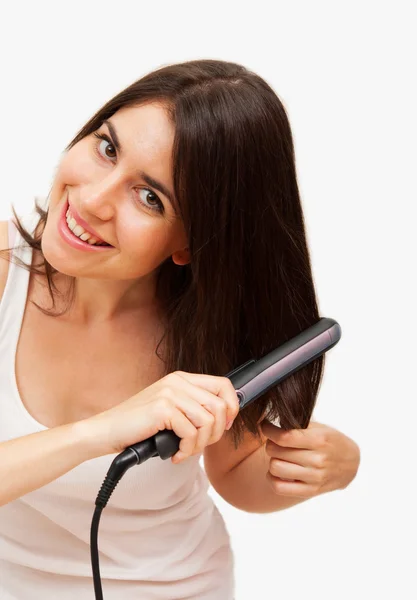 Smiling young woman straightening her hair — Stock Photo, Image
