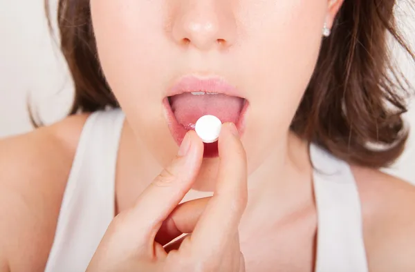 Junge Frau nimmt Tabletten Stockbild