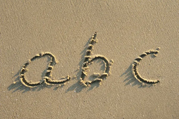 用沙子在沙滩上手写的字母字母 — 图库照片
