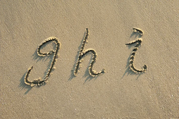 Alfabet brieven handgeschreven in zand op het strand — Stockfoto
